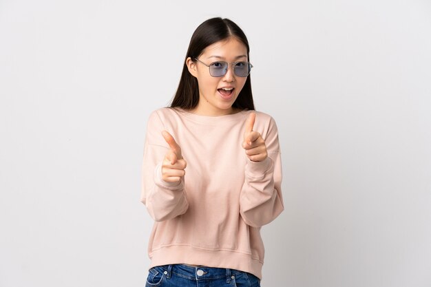 Young Chinese girl over isolated white wall pointing to the front and smiling