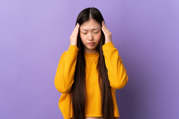 Young Chinese girl over purple wall with headache