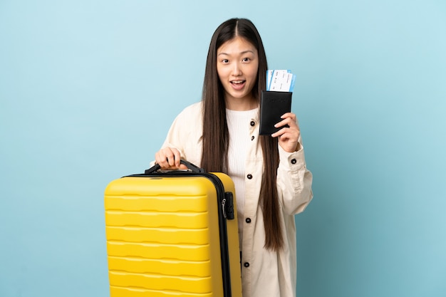 Young Chinese girl over in vacation with suitcase and passport