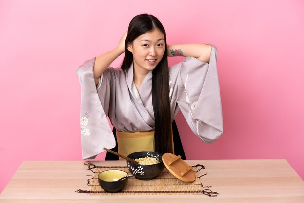 Young Chinese girl wearing kimono and eating noodles laughing