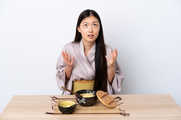 Young Chinese girl wearing kimono and eating noodles stressed overwhelmed