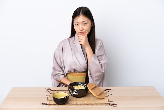 Young Chinese girl wearing kimono and eating noodles thinking