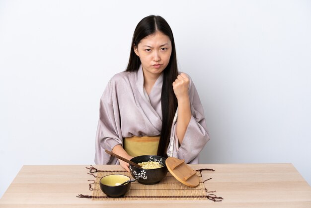 Young Chinese girl wearing kimono and eating noodles with unhappy expression