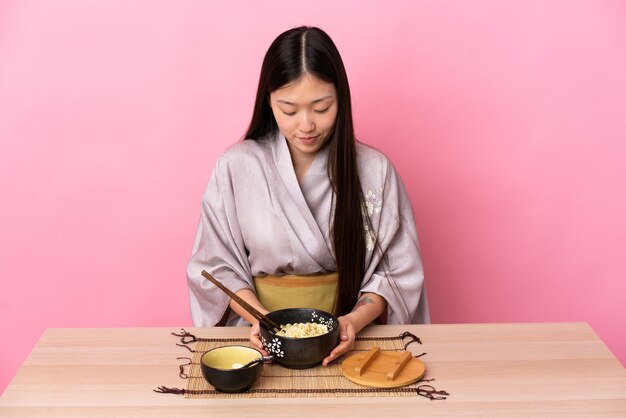 Young Chinese girl wearing kimono and eating noodles