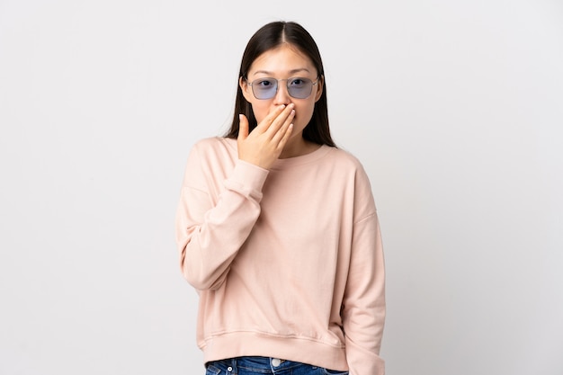 Young Chinese girl over white wall happy and smiling covering mouth with hand