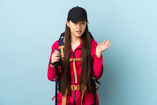 Young Chinese girl with backpack and trekking poles isolated