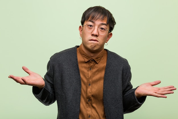 Young chinese man against a green wall