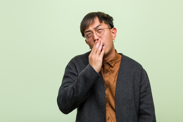 Young chinese man against a green wall