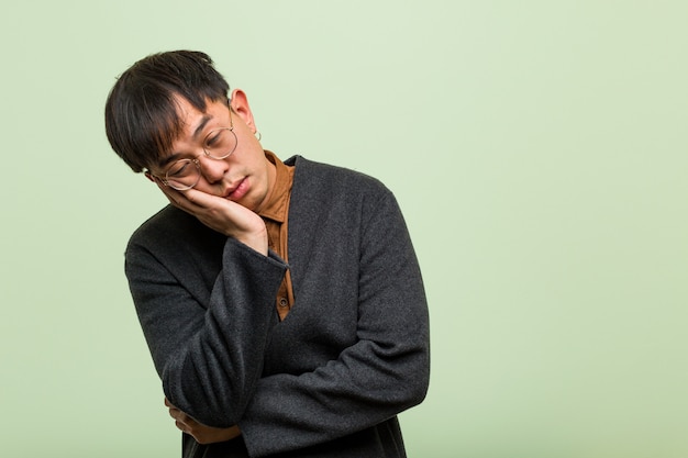 Young chinese man against a green wall