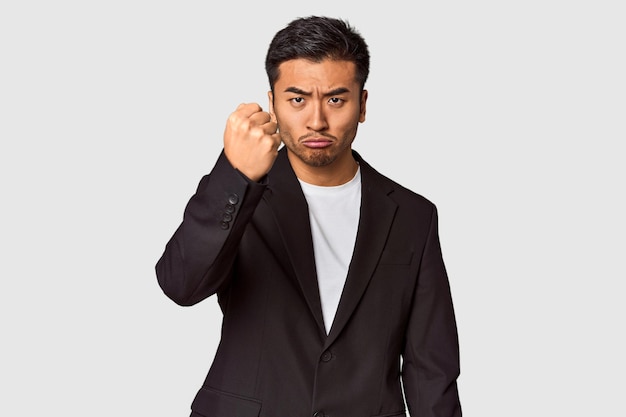 Photo young chinese man in business suit in studio showing fist to camera aggressive facial expression