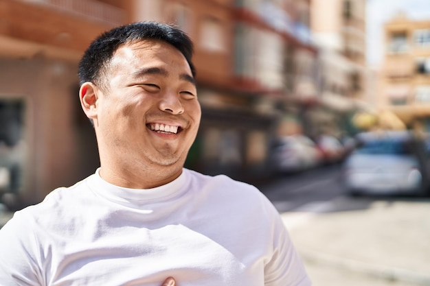 거리에서 자신 있게 서 웃는 젊은 중국 남자