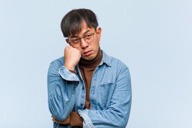 Young chinese man thinking of something, looking to the side