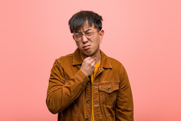 Young chinese man wearing a jacket coughing, sick due a virus or infection