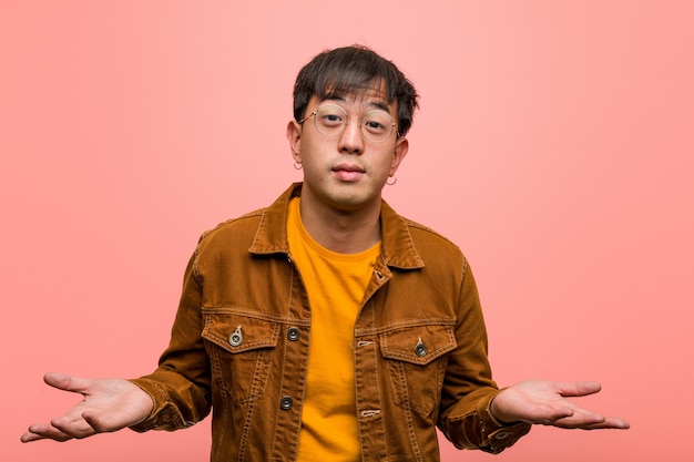 Young chinese man wearing a jacket inviting to come