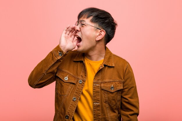 Photo young chinese man wearing a jacket whispering gossip undertone