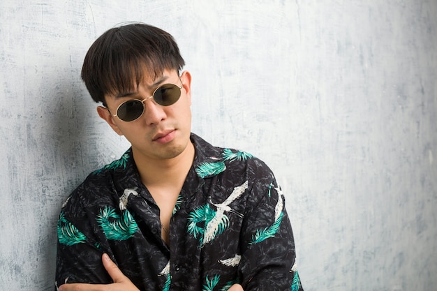 Young chinese man wearing summer outfit crossing arms relaxed