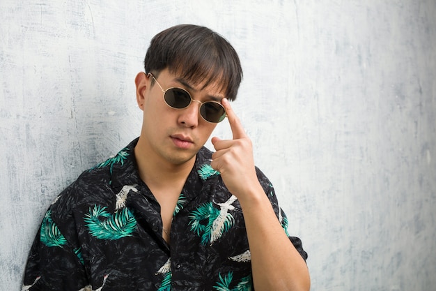 Young chinese man wearing summer outfit doing a concentration gesture