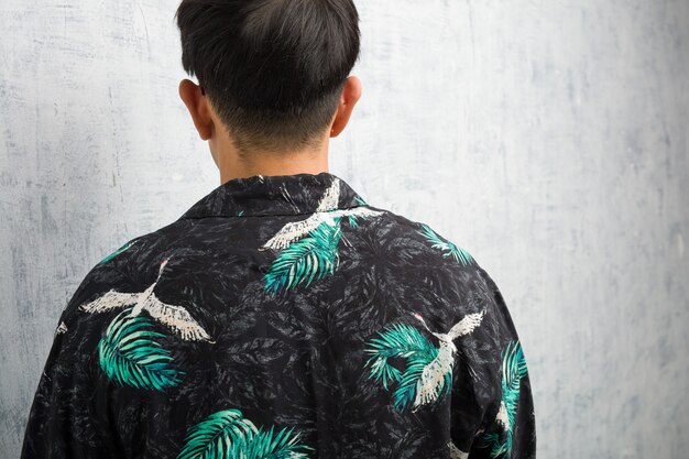 Young chinese man wearing summer outfit from behind, looking back