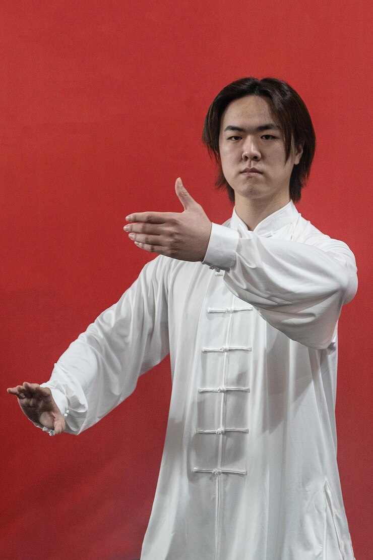Photo a young chinese man in a white kimono practicing taijiquan vertical photo