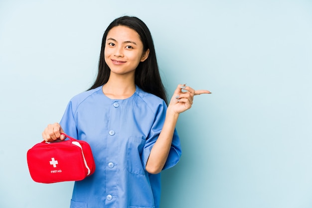 젊은 중국 간호사 여자 머리 뒤로 만지고, 생각 하 고 선택을 파란색 벽에 격리.