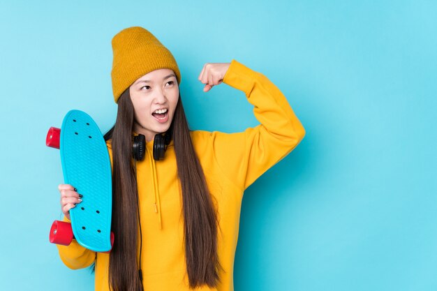 Young chinese skater woman isolated raising fist after a victory, winner concept.