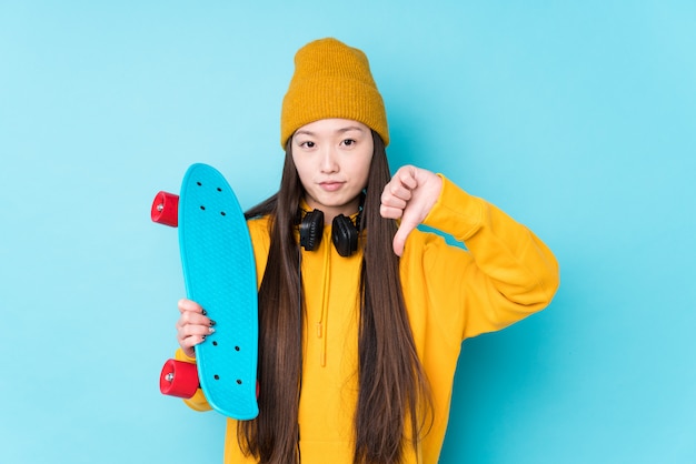 Photo young chinese skater woman isolated showing a dislike gesture, thumbs down. disagreement concept.