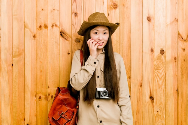 Young chinese traveler woman biting fingernails, nervous and very anxious.