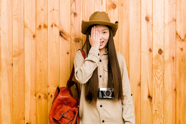 Young chinese traveler woman having fun covering half of face with palm.