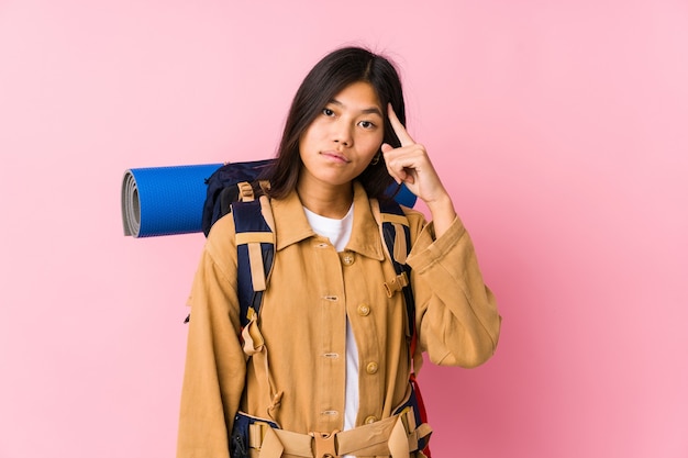 Young chinese traveler woman isolated pointing temple with finger, thinking, focused on a task.