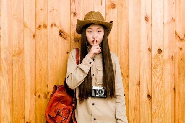 Young chinese traveler woman keeping a secret or asking for silence.