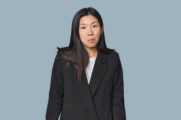 Young Chinese woman in business suit shrugs shoulders and open eyes confused