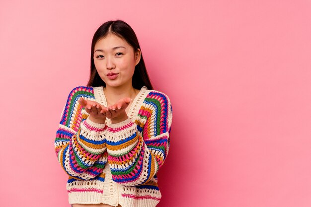 Young chinese woman   folding lips and holding palms to send air kiss.