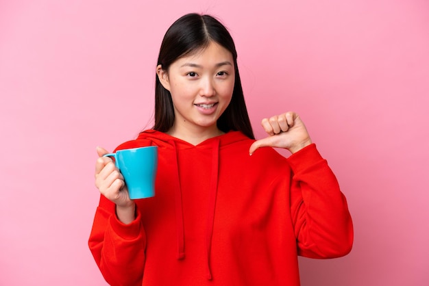 Young Chinese woman holding cup of coffee isolated on pink background proud and selfsatisfied