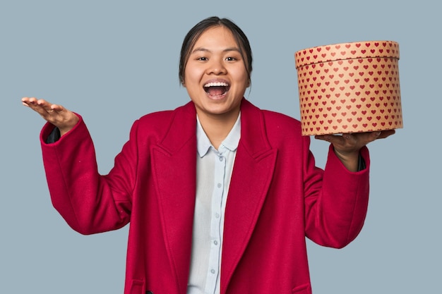 Young Chinese woman holding a heartfilled box receiving a pleasant surprise excited