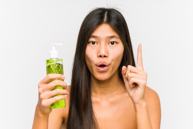 Young chinese woman holding a moisturizer with aloe vera isolated having some great idea, concept of creativity.