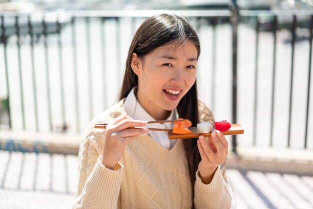 Photo young chinese woman holding sashimi at outdoors