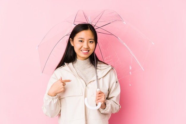 Young chinese woman holding a umbrella person pointing by hand to herself