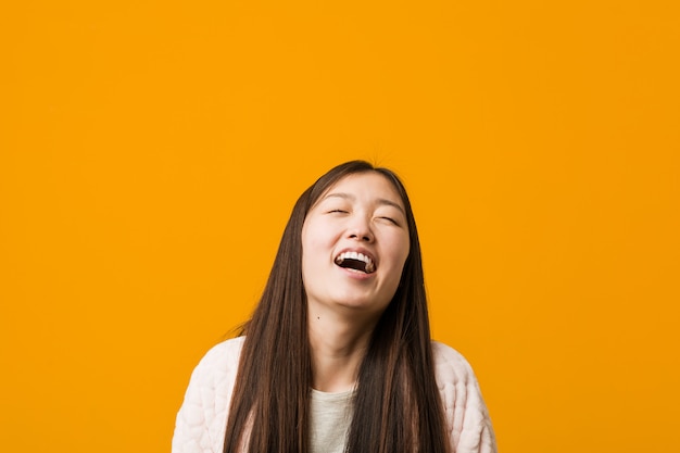 사진 잠 옷 편안 하 고 행복 한 웃음에 젊은 중국 여자, 목 이빨을 보여주는 뻗어.