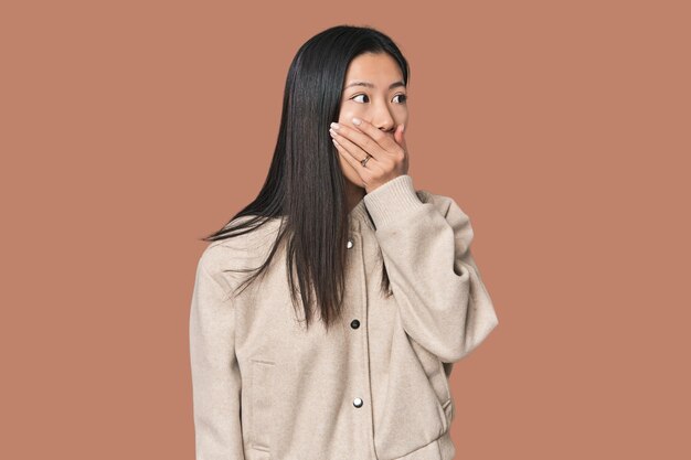 사진 스튜디오 에 있는 젊은 중국인 여자 는 손 으로 입 을 고 있는 복사 공간 을 사려 깊게 바라보고 있다