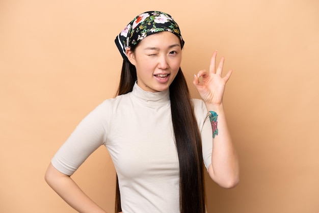 Photo young chinese woman isolated on beige background showing ok sign with fingers