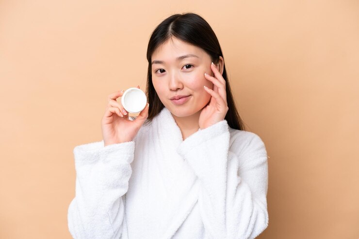 Photo 保湿剤とベージュの背景に分離された若い中国人女性
