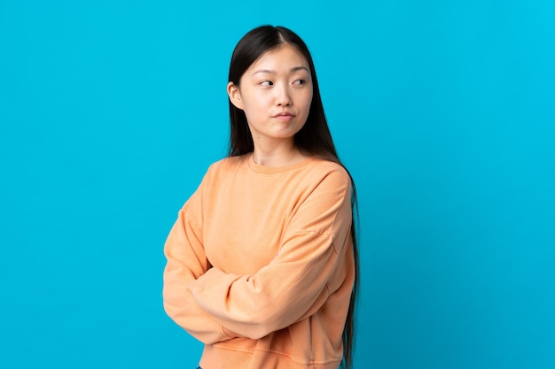 Young Chinese woman over isolated blue keeping the arms crossed