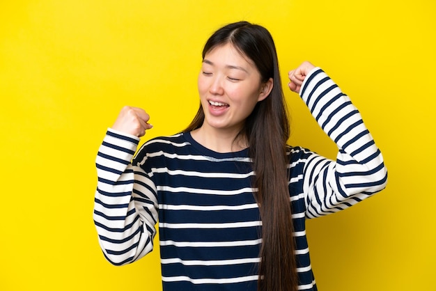 写真 勝利を祝う黄色の背景に分離された若い中国人女性