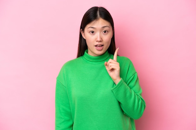 Young Chinese woman isolated on pink background intending to realizes the solution while lifting a finger up