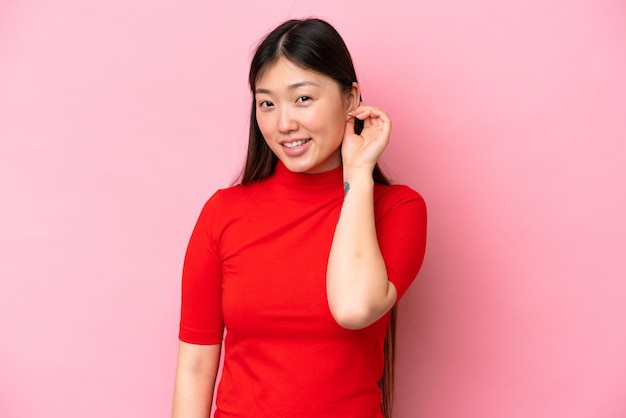 웃는 분홍색 배경에 고립 된 젊은 중국 여자