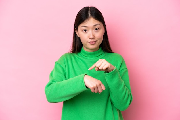 Young Chinese woman isolated on pink background making the gesture of being late