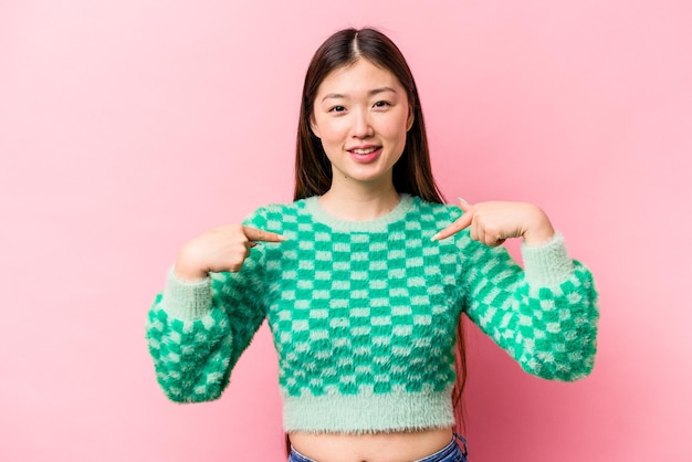 Young Chinese woman isolated on pink background points down with fingers positive feeling