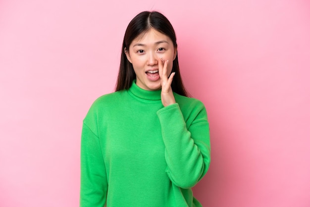 Young Chinese woman isolated on pink background shouting with mouth wide open