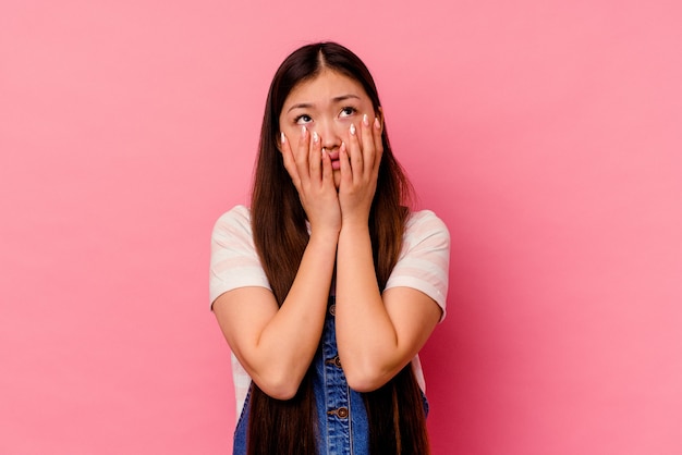 Young chinese woman isolated on pink background whining and crying disconsolately.