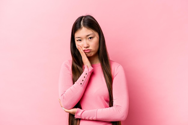 Young Chinese woman isolated on pink background who is bored fatigued and need a relax day